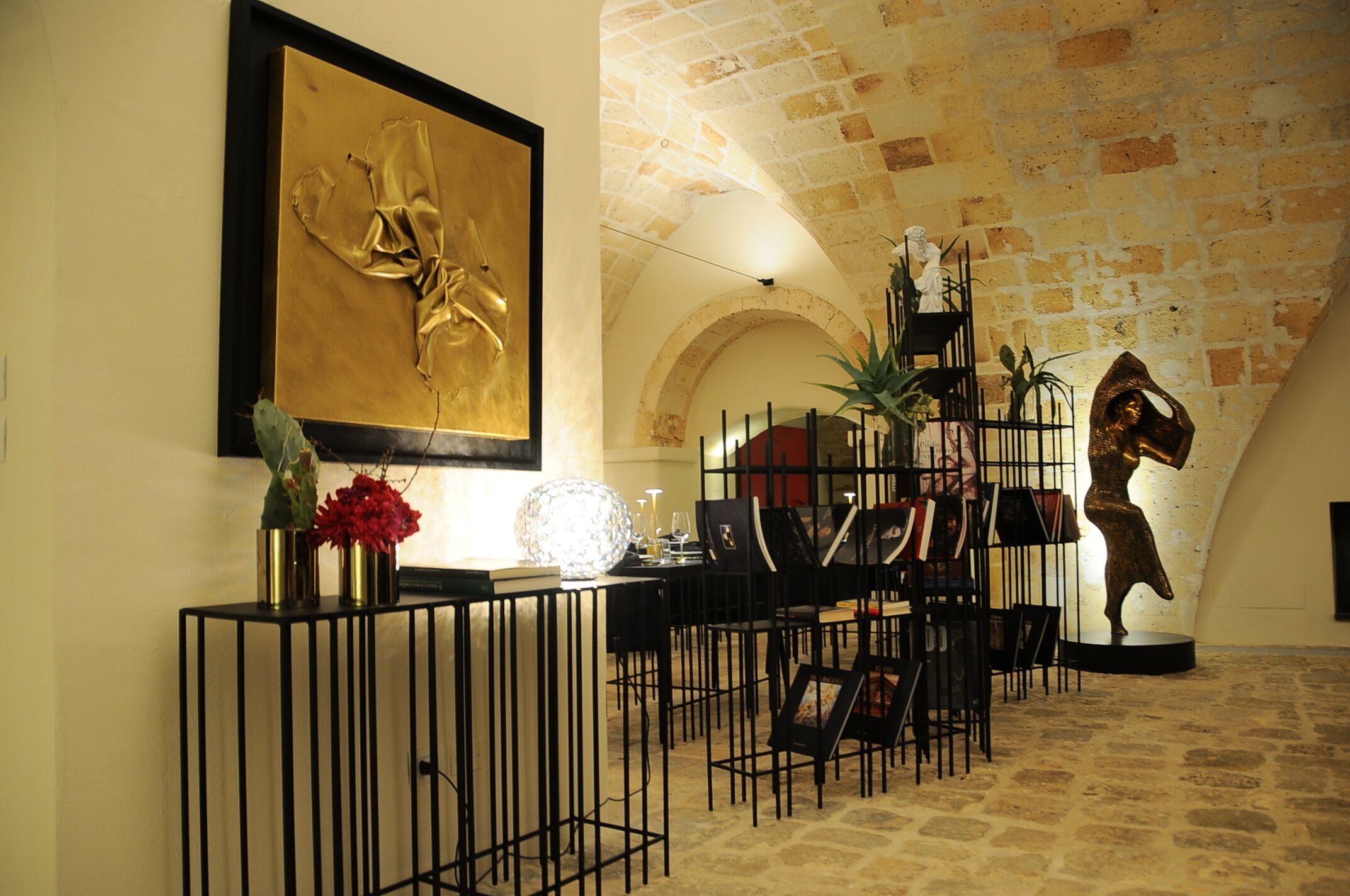 A reception area with a black console table, a framed artwork, and a statue.