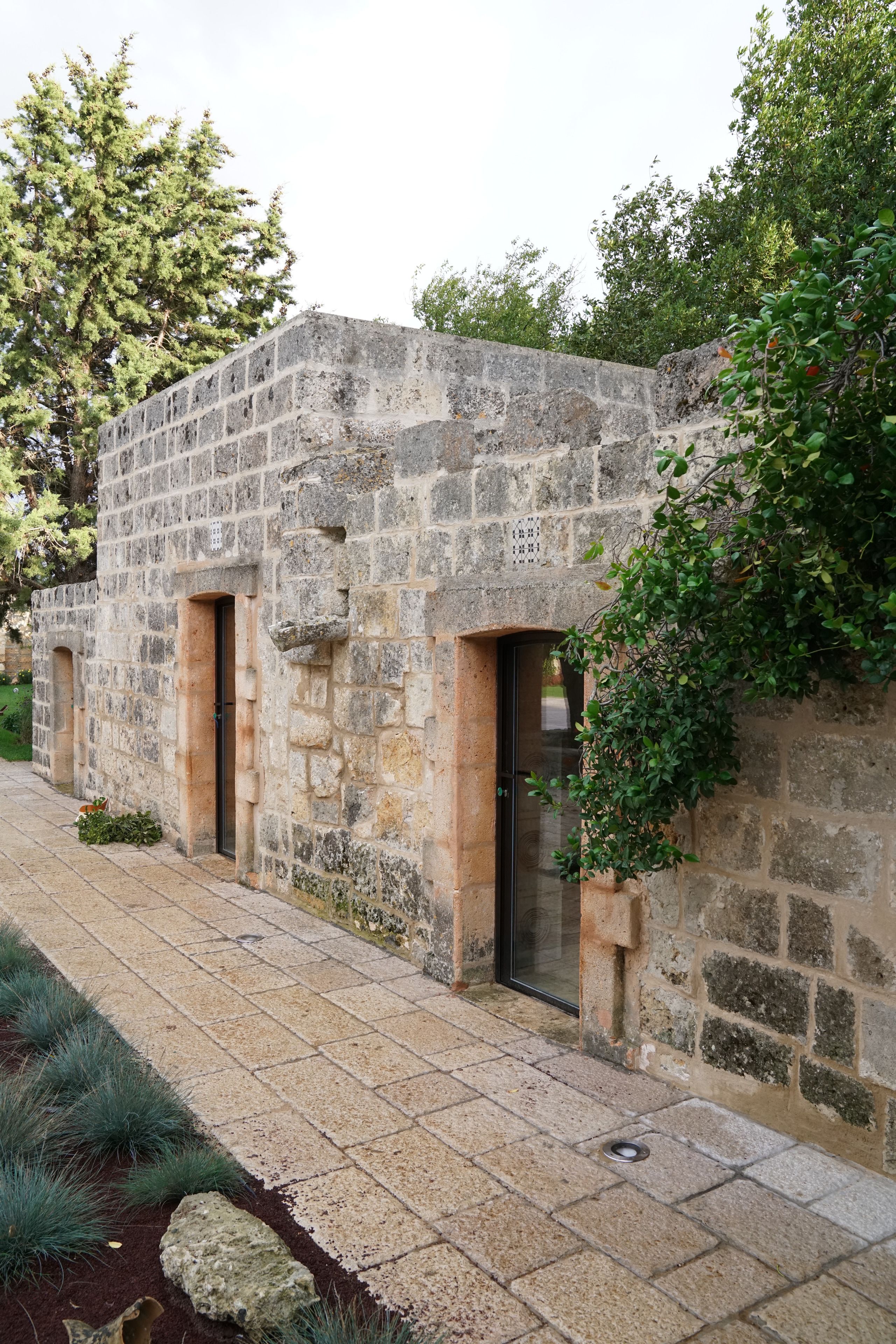 A stone building with three arched doorways and a small window.