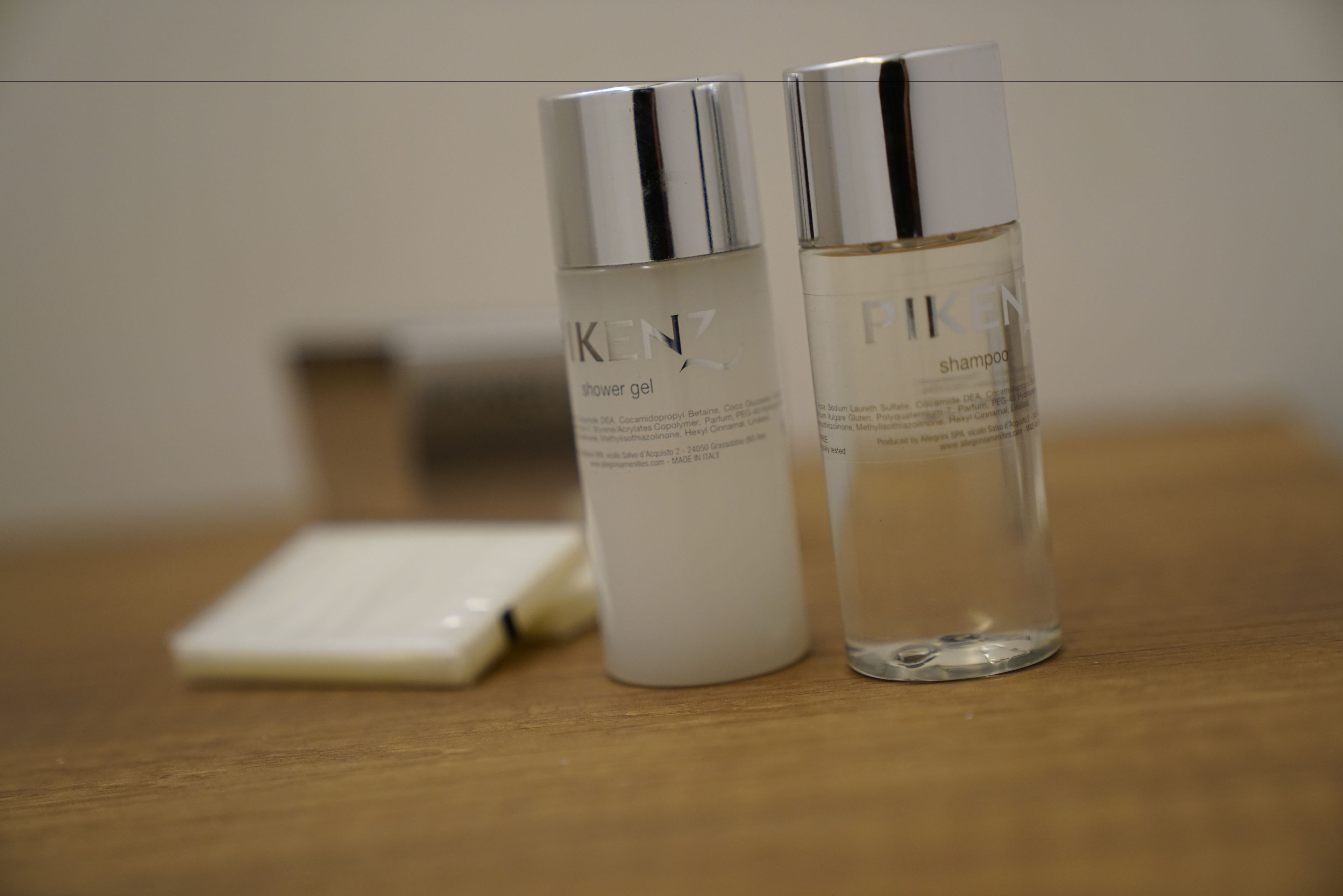 Two bottles of Kenzo shower gel and shampoo on a wooden surface.