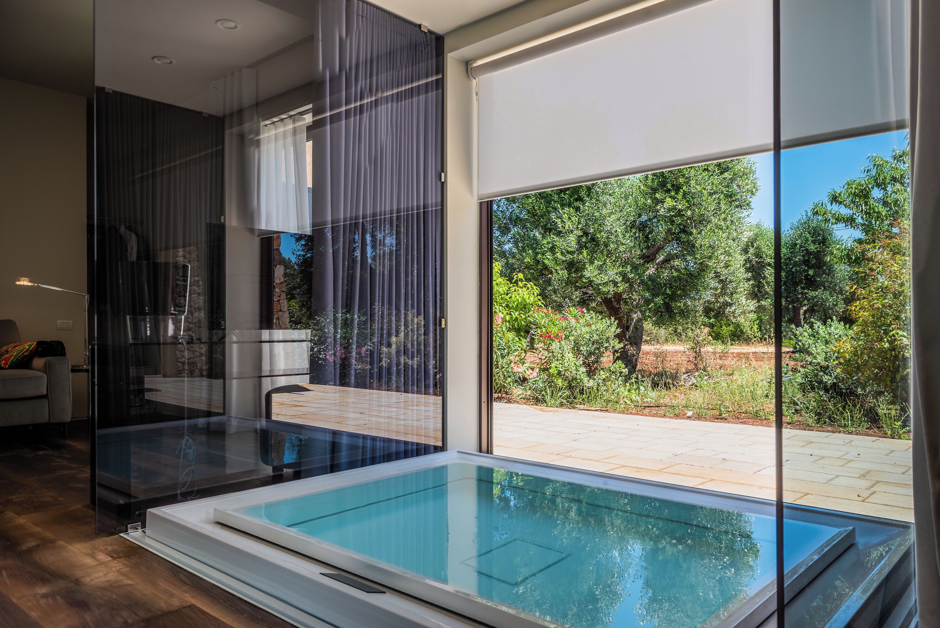 A modern interior with a glass-enclosed pool, large windows, and a view of the outdoors.