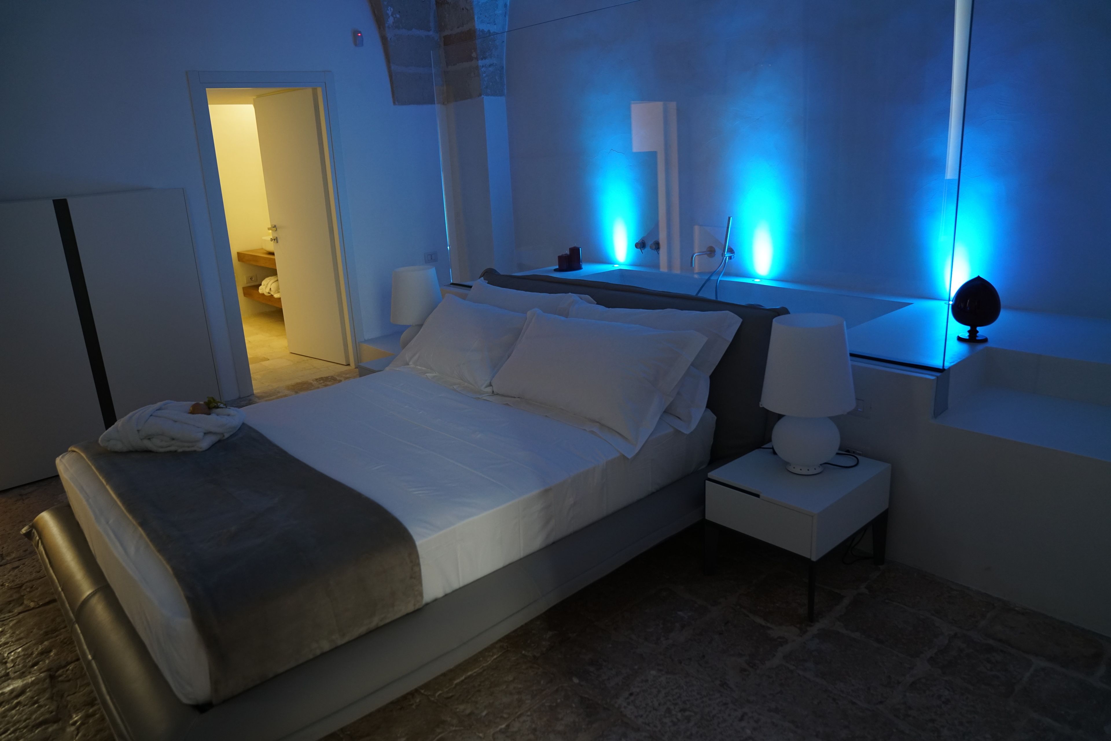 A modern bedroom with a bed, bedside tables, and a mirror.