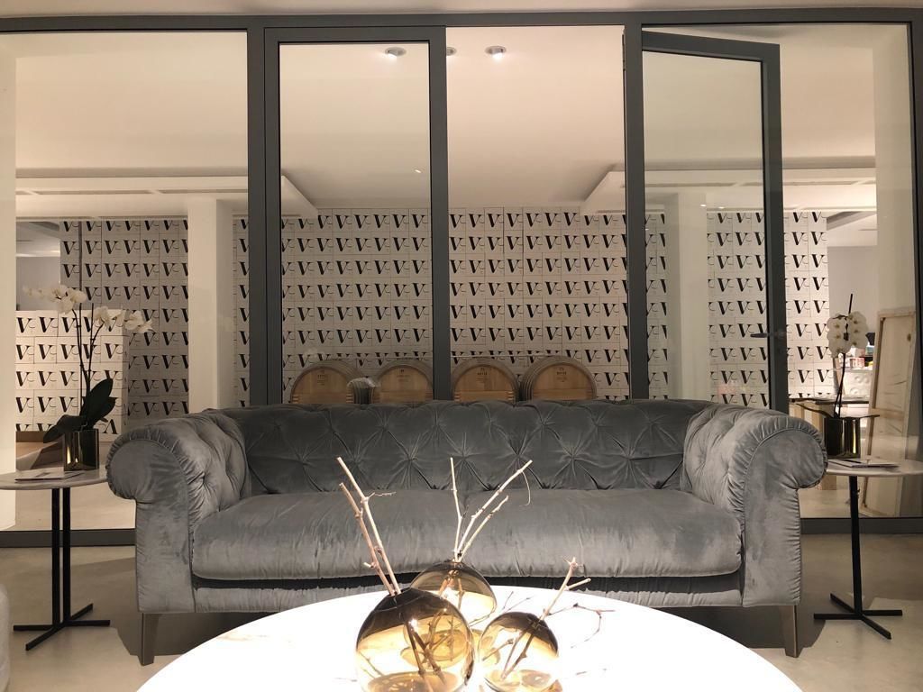 A modern living room with a grey sofa, a round table with decorative items, and patterned wallpaper.