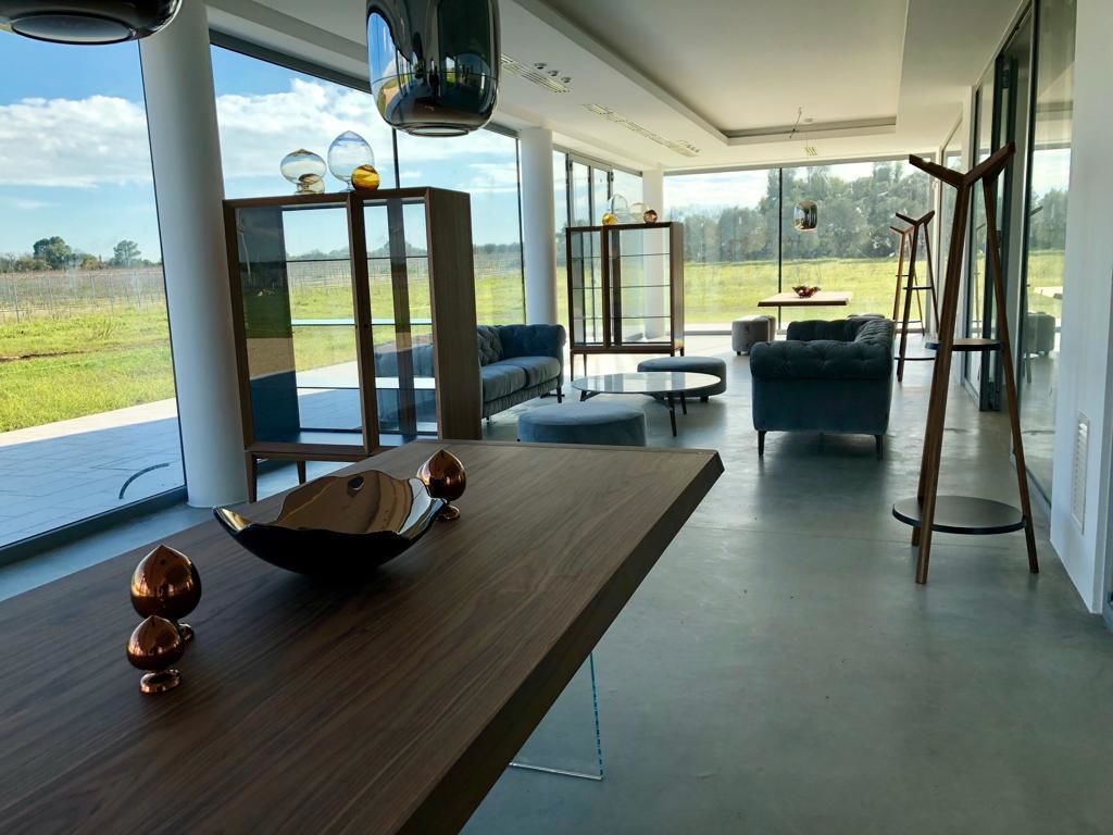A spacious living area with a wooden table, seating, and large windows offering a view of the outdoors.