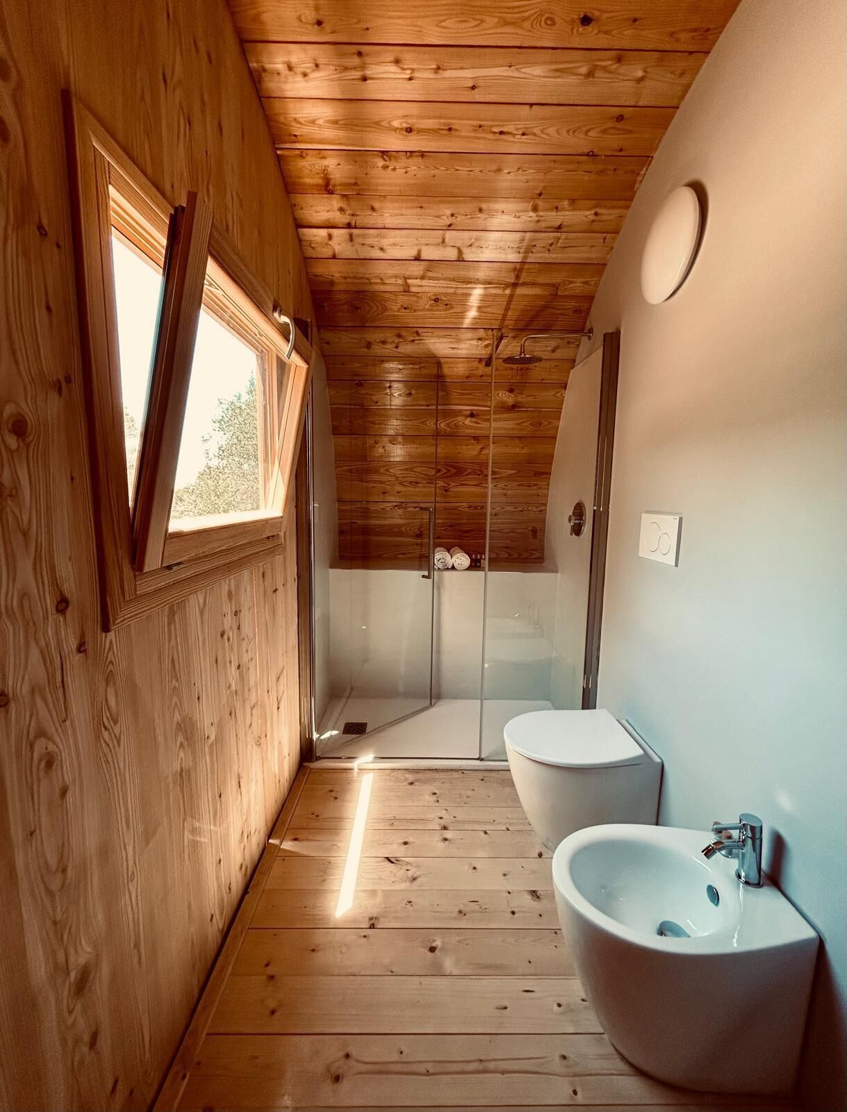Ein Holzinnenraum mit Dusche, zwei Waschbecken und einem Fenster.