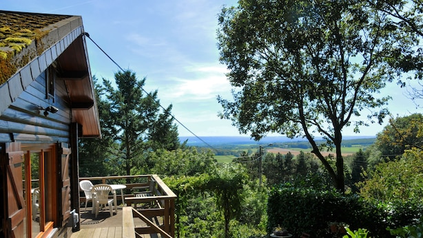A wooden deck with outdoor seating, overlooking a lush landscape and distant fields. - Les Vignes (Durbuy)