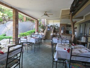 A restaurant with outdoor seating, brick pillars, and a staircase leading to an upper level.