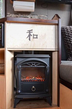 A wood-burning stove with a decorative front panel and a wooden drawer above it. - Seattle Glamping - Zen Den (Seattle)