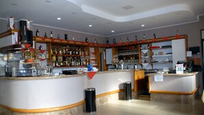 A bar area with a curved counter, shelves with bottles, and a trash bin. - Il Calipso by Mago (Turbigo)