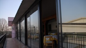 A balcony with a table and chairs, a glass door, and a view of a building across the street. - Il Calipso by Mago (Turbigo)