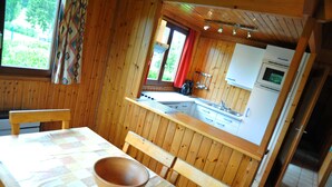 Cocina de cabaña de madera con una mesa de comedor, sillas y un ventanal grande.