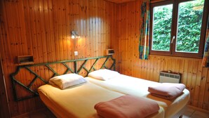 Una habitación con paneles de madera, una cama, un ventanal y un calentador de pared.