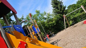 A playground with a yellow slide and red and blue play structures. - La Tanière (Somme-Leuze)