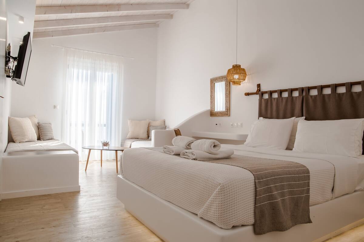 A modern hotel room with a large bed, a small table, and a TV mounted on the wall.