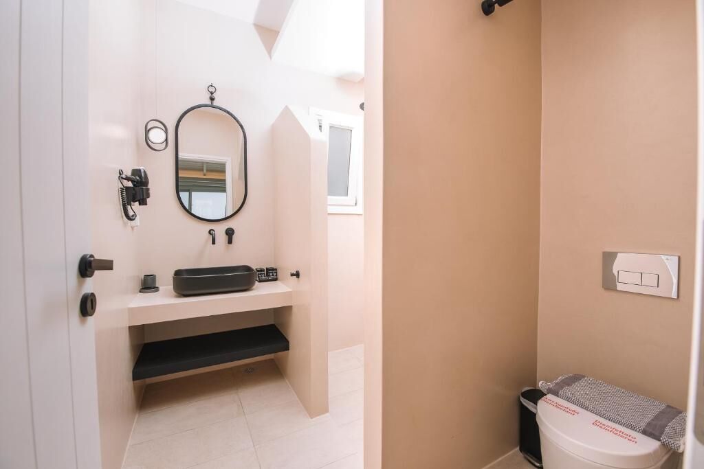 A bathroom with a sink, mirror, towel rack, and a toilet.