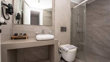 Et stilfuldt badeværelse med et stort spejl, vask, toilet og bruseområde.