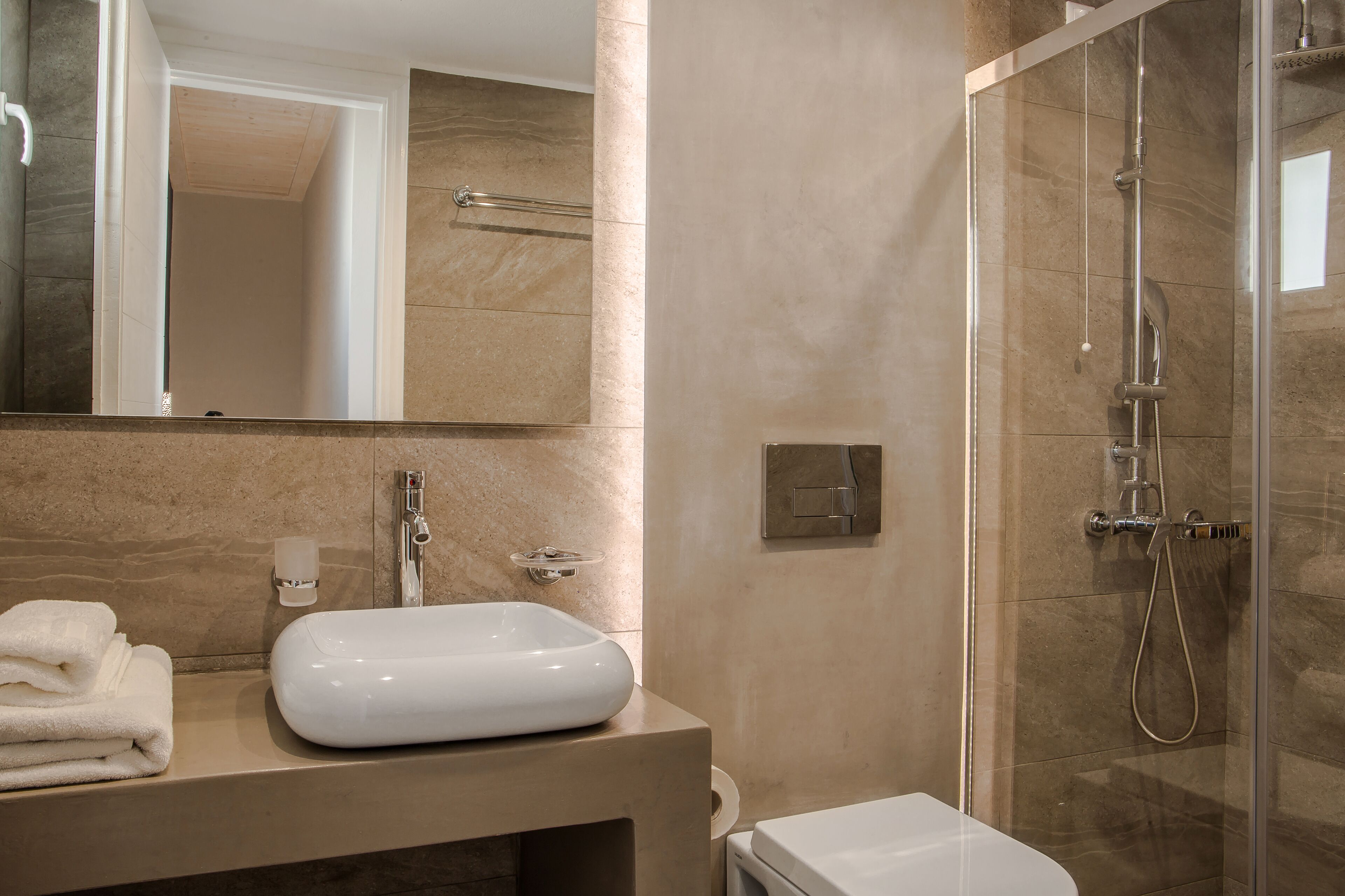 A modern bathroom with a glass-enclosed shower, a white sink, and a toilet.