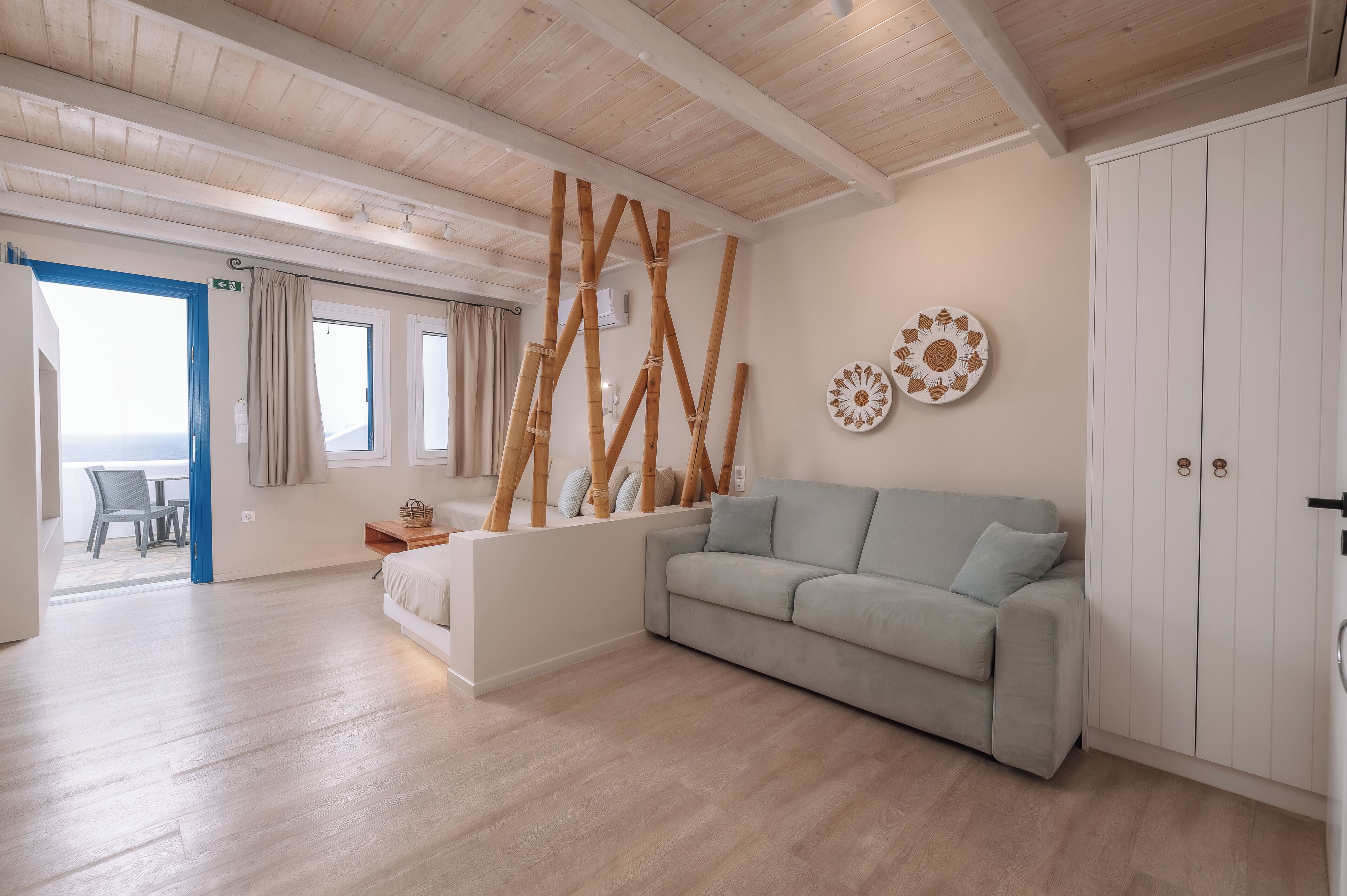 Una sala moderna con un sofá de color claro, un panel de madera y un armario blanco.