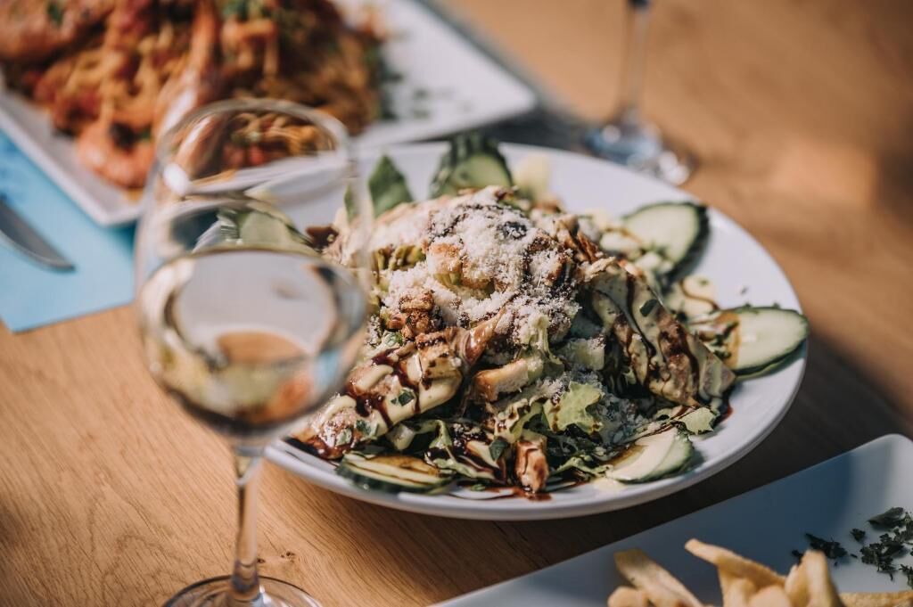 A dining table with plates of food, a glass of wine, and a napkin.