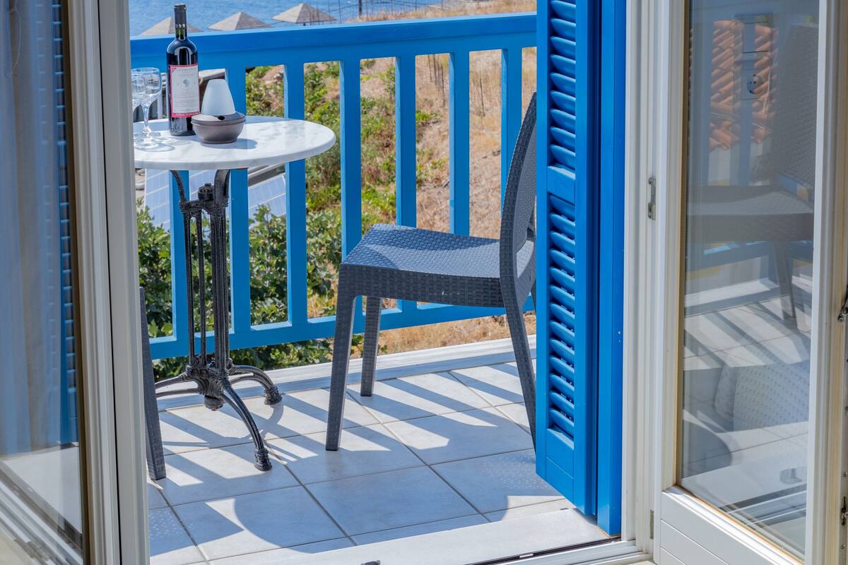 A balcony with a table and chair, overlooking the sea.