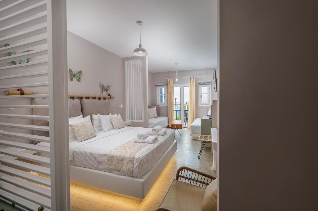 A modern bedroom with a large bed, bedside tables, a wardrobe, and a view of the outdoors.
