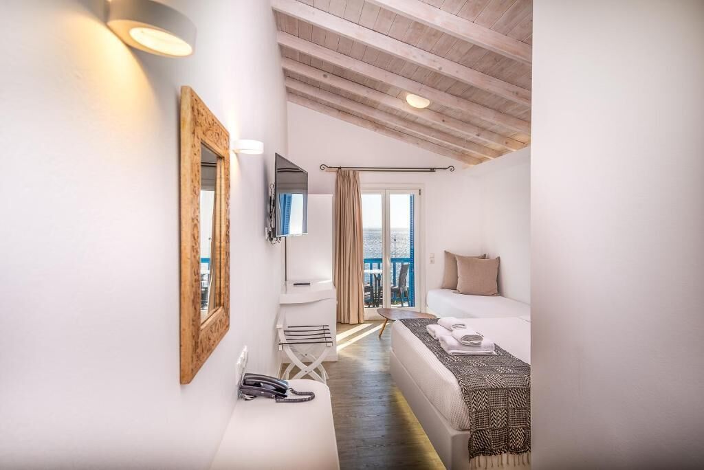 Habitación de hotel con cama, televisión, escritorio, silla, teléfono y vistas al exterior.