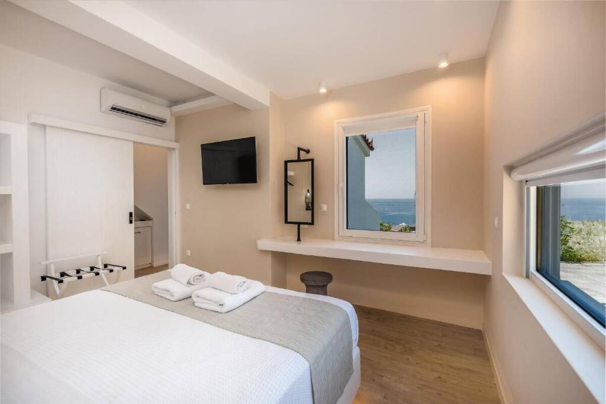 A bedroom with a bed, a TV, a window with a view, a mirror, and a shelf.