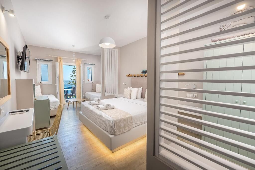 Habitación de hotel moderna con una cama grande, un escritorio, una silla y vistas al exterior.