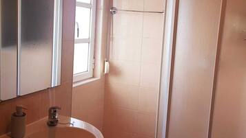 A bathroom with a sink, mirror, and shower.