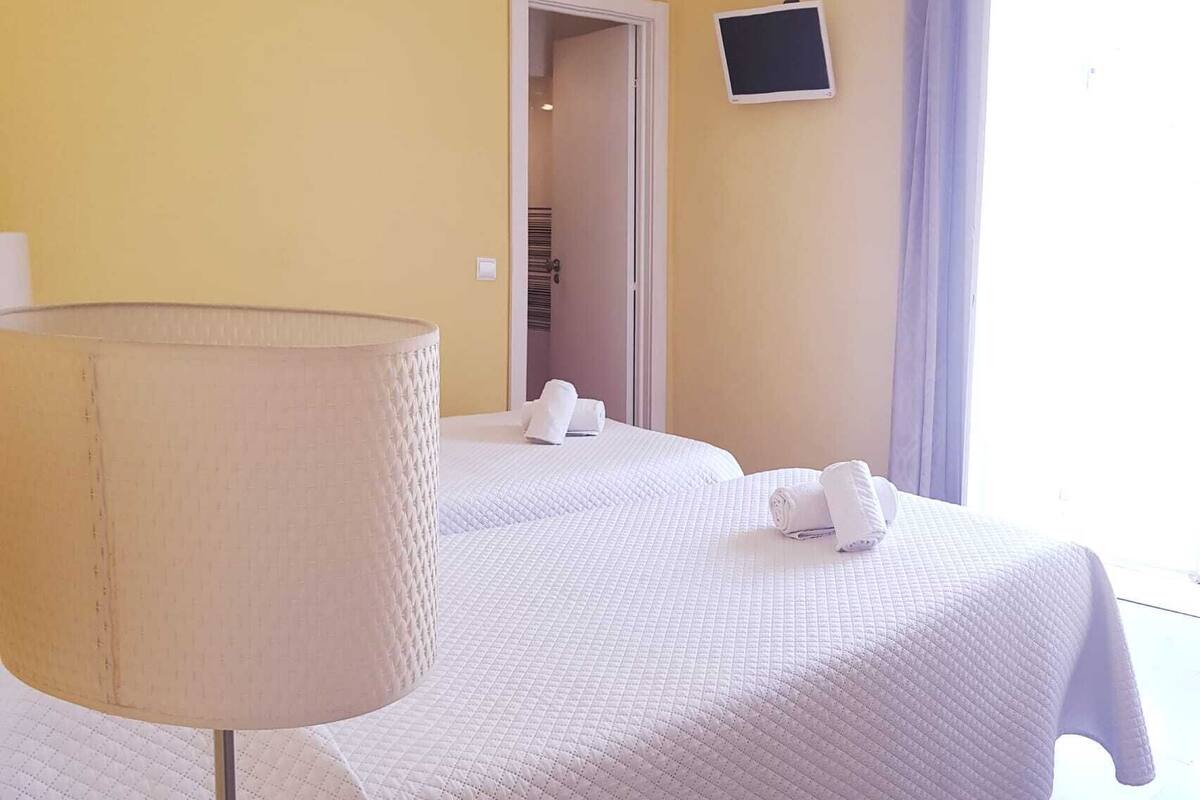 A hotel room with a bed, a bedside lamp, a TV, and a window with curtains.