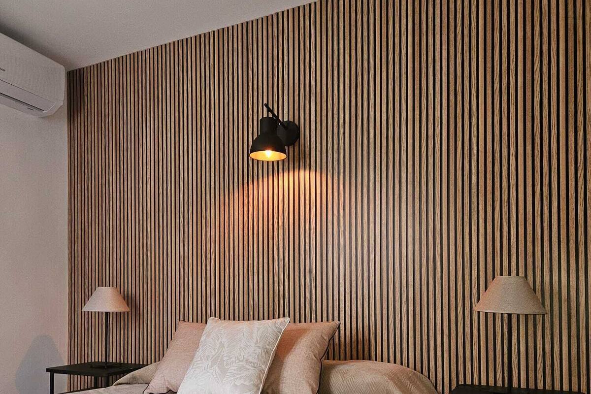 A bedroom with a large bed, two bedside tables, and a wall-mounted lamp.