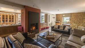 Un salon chaleureux avec une cheminée, des canapés en cuir, une table basse et un mur en briques.