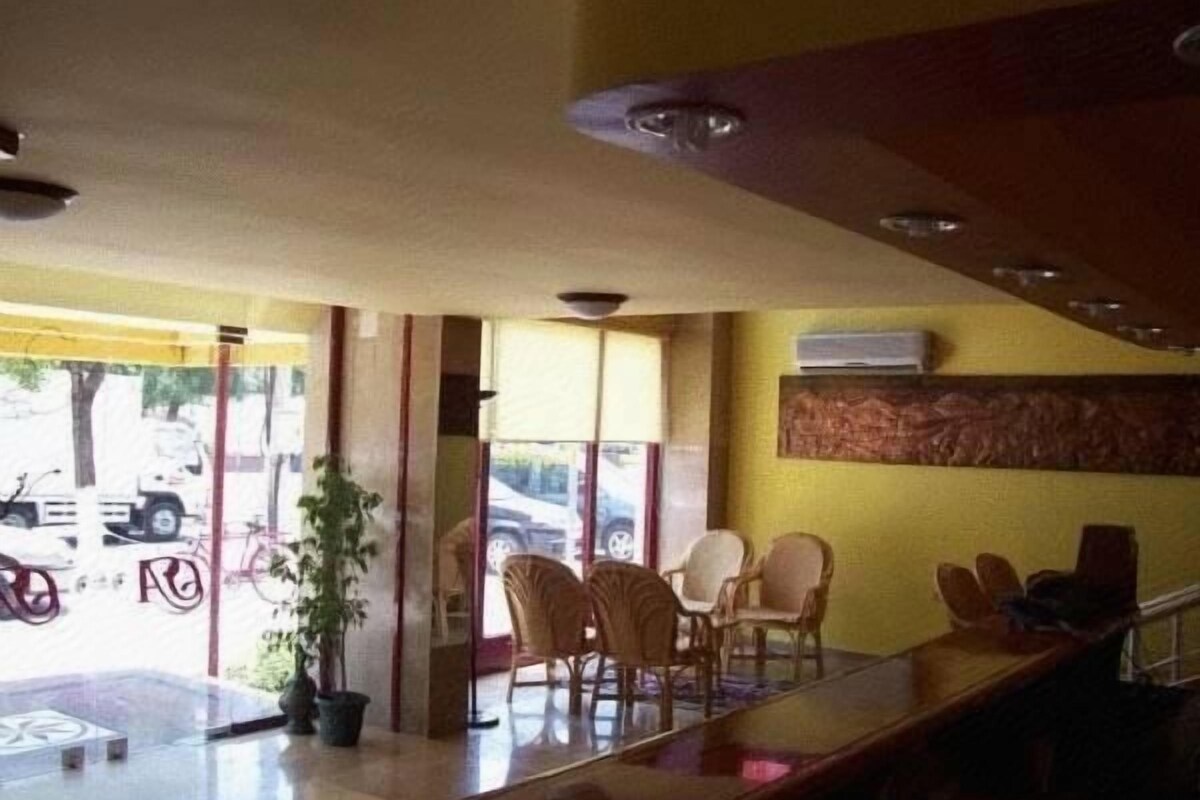 Un vestíbulo de hotel con recepción, zona de estar y vistas a la calle.