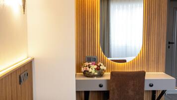 Ein Hotelzimmer mit einem Bett, einem Schreibtisch mit Spiegel und einer Blumenvase.