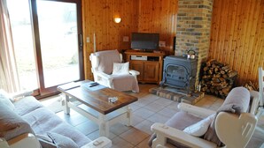 A cozy room with wooden walls, a television, a fireplace, and comfortable seating. - Wilgenhof (Hotton)