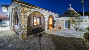 A stone building with arched doorways and a small annex with a conical roof. - La cutizza (Martina Franca)
