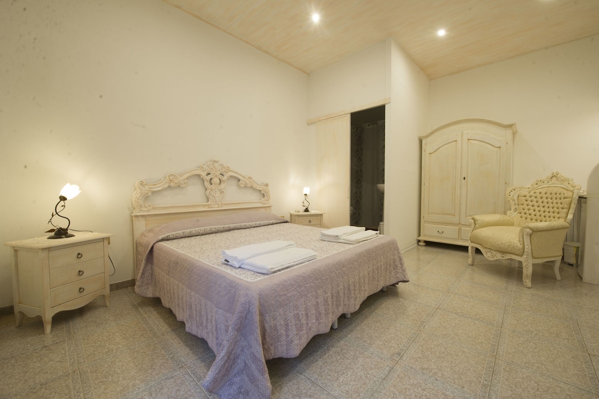 Une chambre à coucher avec un grand lit, une table de chevet, une armoire et une chaise.