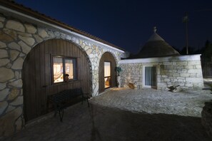 A stone building with arched doors and a small porch area. - La cutizza (Martina Franca)