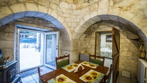 A stone-walled room with a dining table set for two, a wooden cabinet, and a radiator. - La cutizza (Martina Franca)