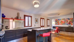 Una cocina moderna con una isla central, taburetes de bar y vistas al área de estar.