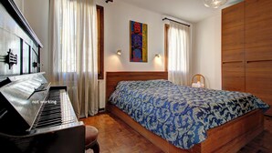 Un dormitorio con un piano, una cama con colcha estampada y un armario de madera.