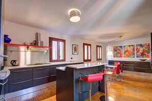 Una cocina moderna con una isla central, taburetes de bar y vistas al área de estar.