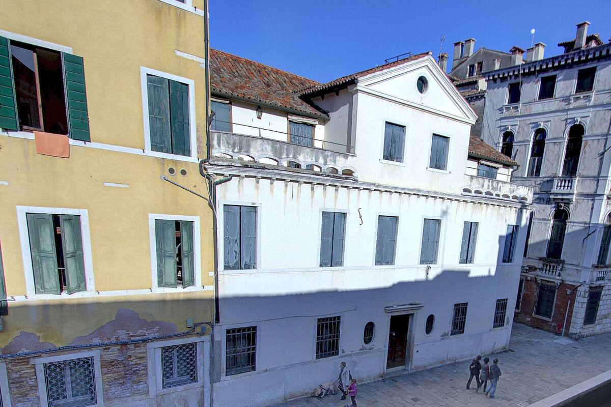 A historic building with multiple windows and balconies, situated along a canal.
