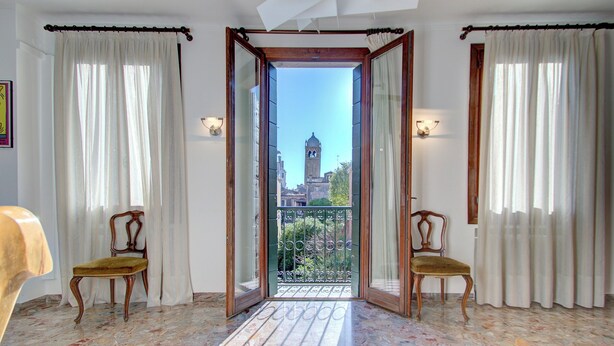 Habitación con balcón, dos sillas y vistas a una torre.
