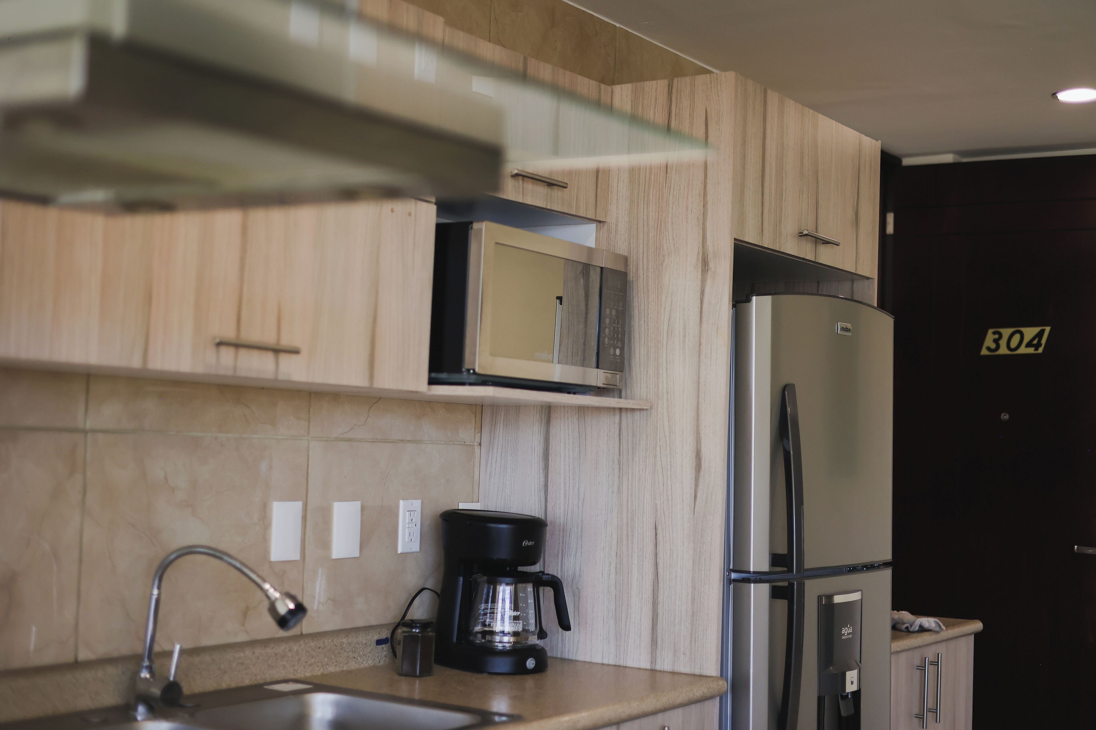 Una cocina moderna con microondas, refrigerador y cafetera.