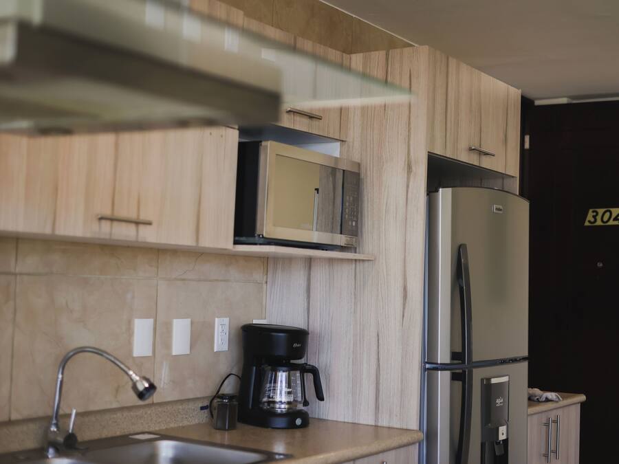 Una cocina moderna con microondas, refrigerador y cafetera.