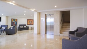 Eine großzügige Lobby mit glänzendem Boden, einer Treppe und modernen Sitzbereichen.