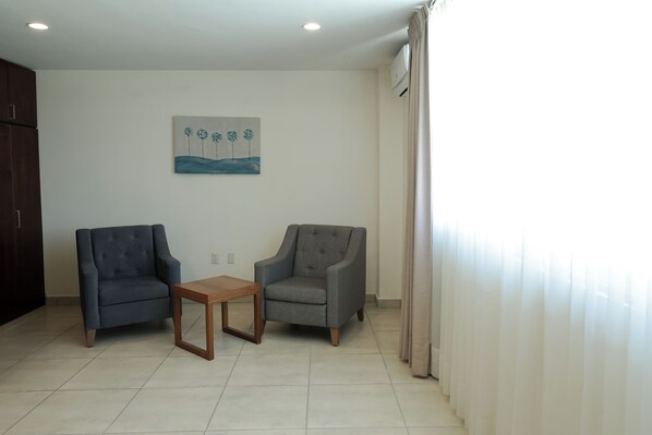 A living room with two grey armchairs, a wooden coffee table, and a painting on the wall. - Suites San Pedro (Zacatecas)