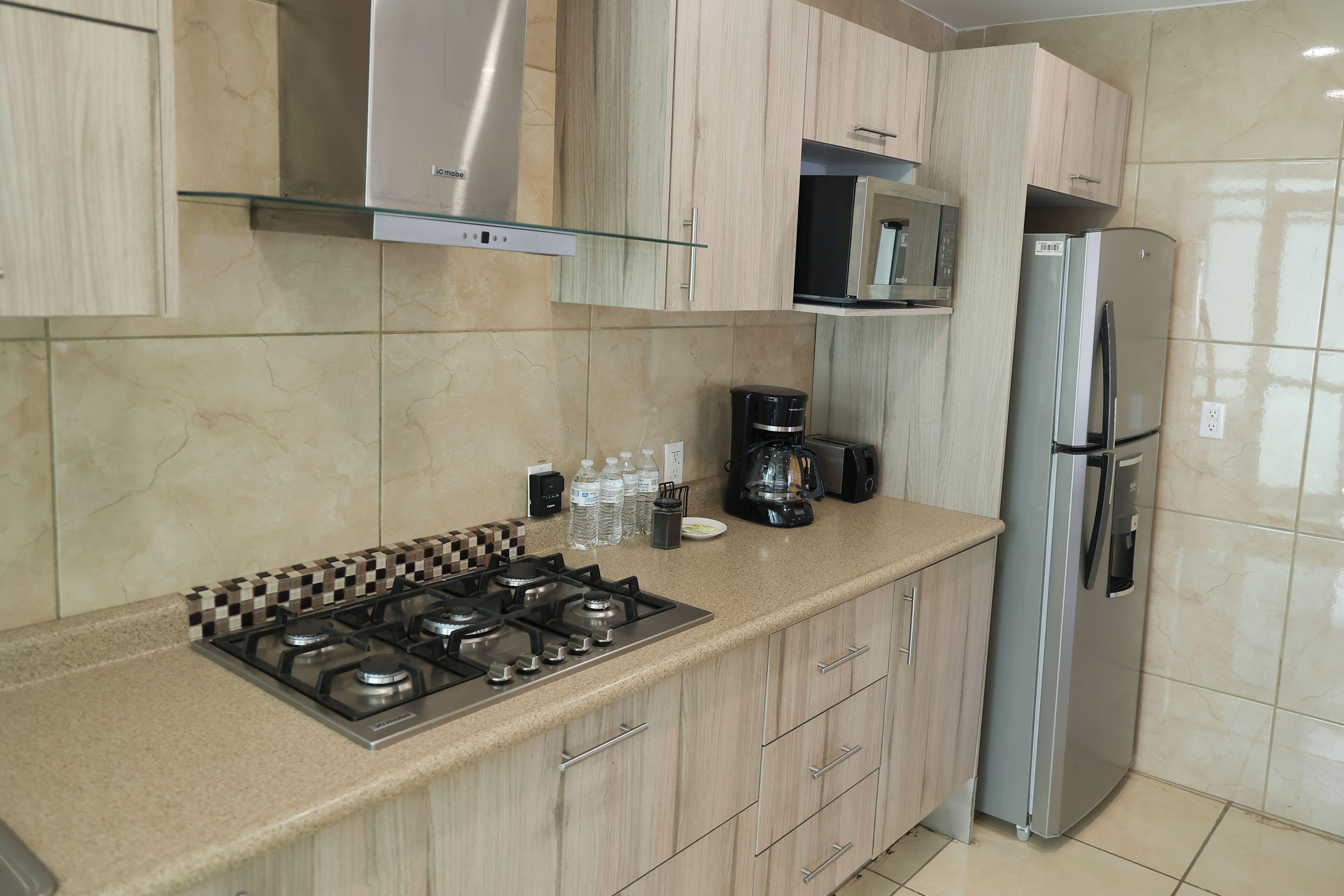 Una cocina moderna con estufa a gas, electrodomésticos de acero inoxidable y armarios de madera clara.
