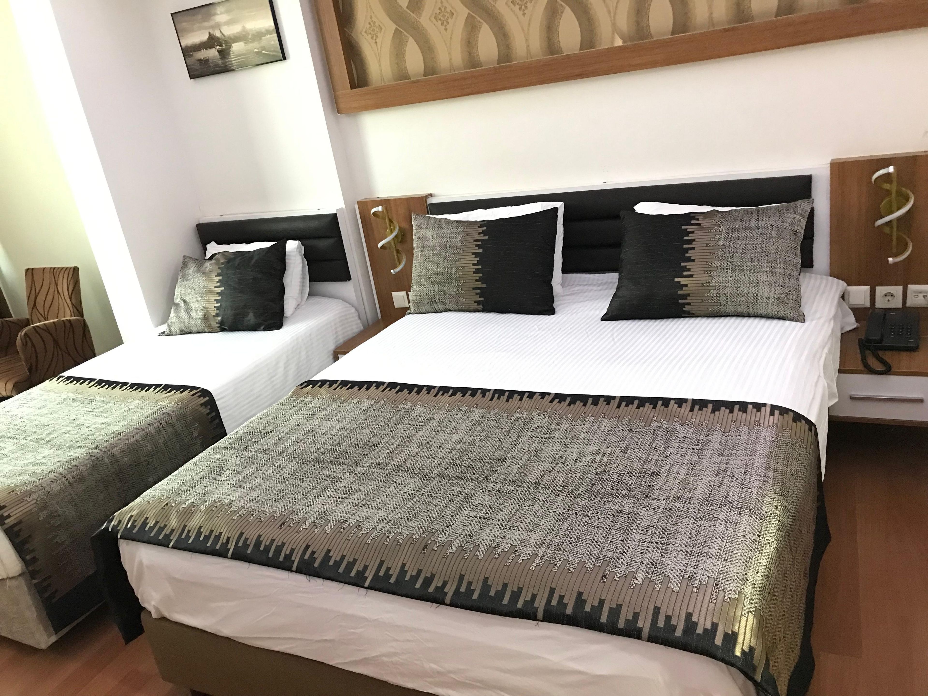 Habitación de hotel con dos camas, cabecero de madera, teléfono y un cuadro en la pared.