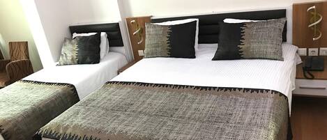 Habitación de hotel con dos camas, cabecero de madera, teléfono y un cuadro en la pared.